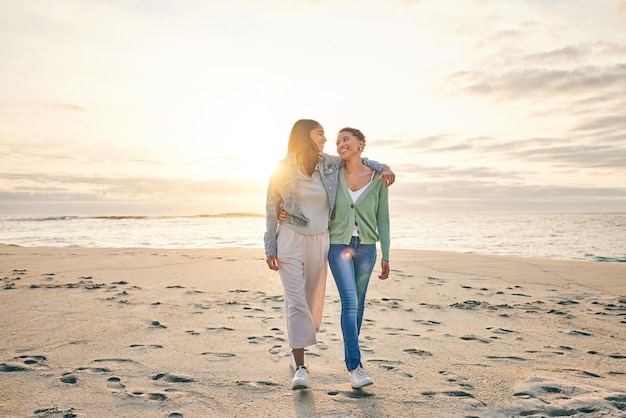 Ama la spiaggia e la coppia lesbica al tramonto che cammina insieme sulla sabbia mockup vacanza al tramonto e abbraccio all'appuntamento Donne Lgbt che legano e si rilassano in vacanza sull'oceano con romanticismo orgoglio e felice viaggio nella natura