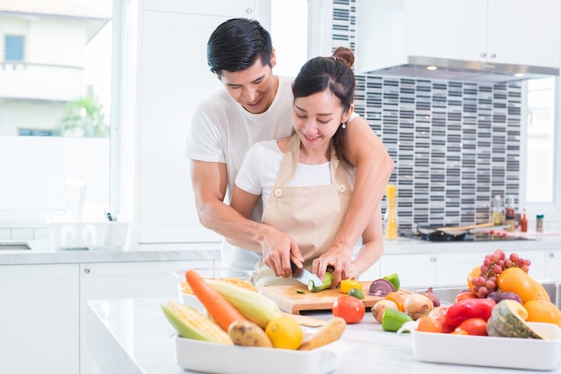 Amanti asiatici o coppia cucina e affettare verdura in cucina