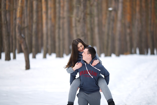 Amanti felici in inverno sullo sfondo del bosco innevato all'aperto