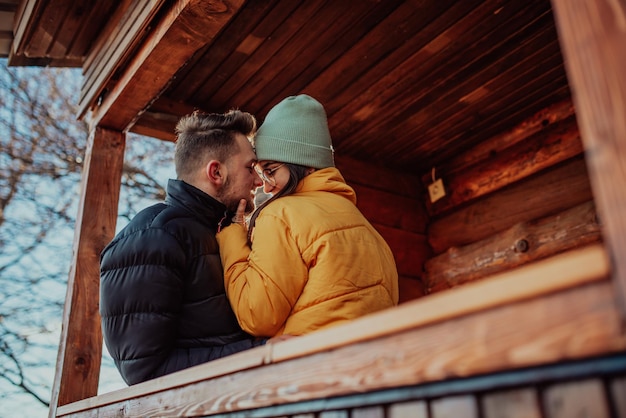 Amare l'uomo e la donna in piedi nel balcone della loro camera cottage