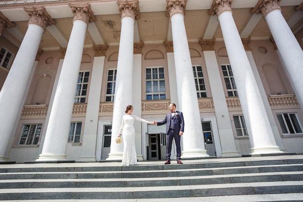 Amare la coppia di sposi novelli passeggiate nella città vecchia vicino alle colonne nel giorno del matrimonio