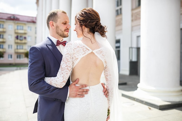 Amare la coppia di sposi novelli passeggiate nella città vecchia vicino alle colonne nel giorno del matrimonio