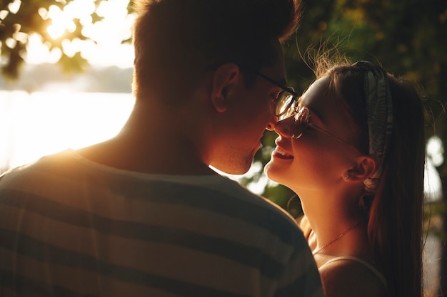 Amare la giovane coppia in piedi vicino faccia a faccia sorridente all'esterno. Giovane donna con le lentiggini sorridente prima di baciare il suo fidanzato.