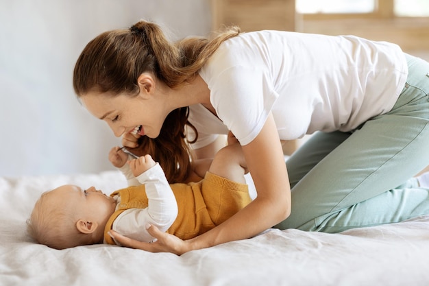 Amare la giovane madre che accarezza il suo simpatico bambino in camera da letto