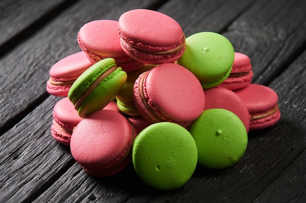 Amaretti colorati e tulipani su un vecchio sfondo di legno.