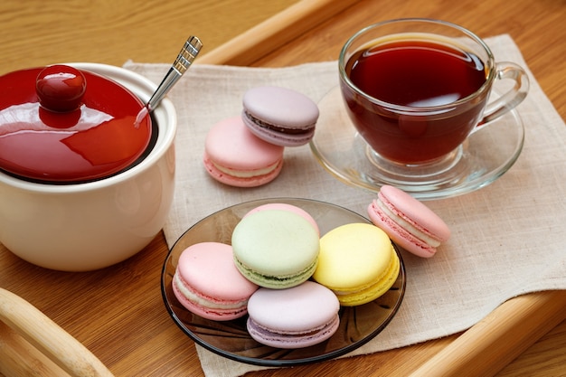 Amaretti colorati e una tazza di tè su un vassoio di legno