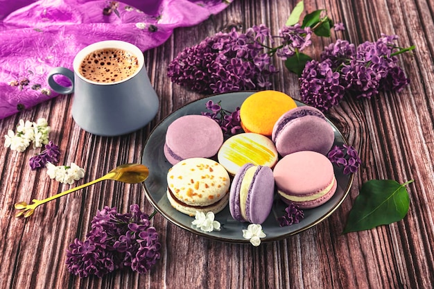 Amaretti da dessert colorati su un piatto con un cucchiaio grigio tazza di caffè sul tavolo Lilla viola