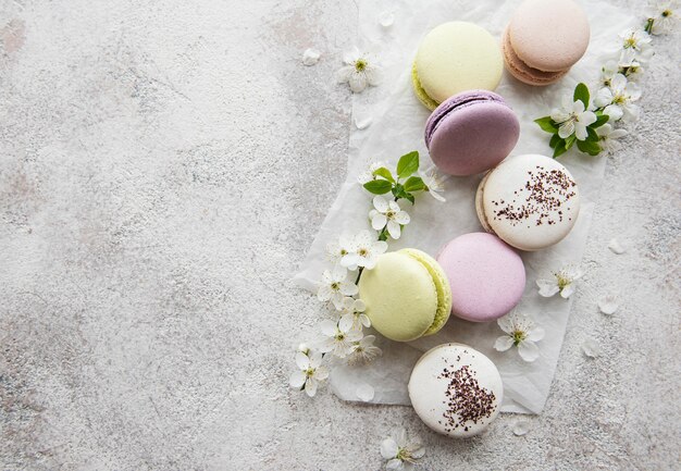 Amaretti dolci francesi varietà colorata su una superficie di cemento con fiori primaverili