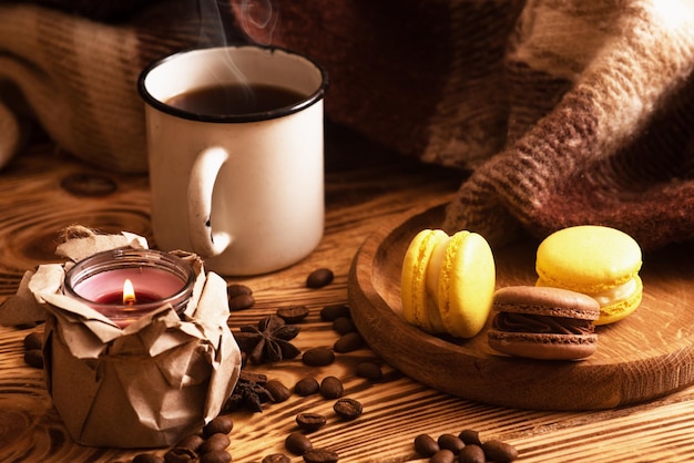 Amaretti dolci su tavola di legno con una tazza di caffè e una candela accesa Foto d'atmosfera Contenuto per i social network