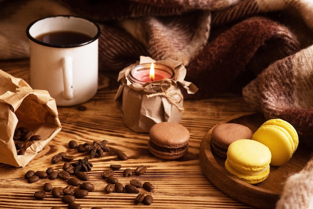 Amaretti dolci su tavola di legno con una tazza di caffè e una candela accesa Foto d'atmosfera Contenuto per i social network