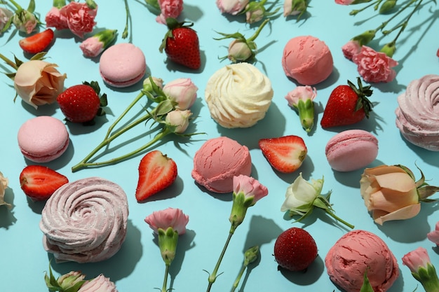 Amaretti, marshmallow, fiori e fragole su sfondo blu