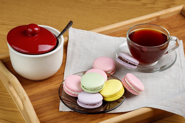 Amaretti multicolori e una tazza di tè su un vassoio di legno