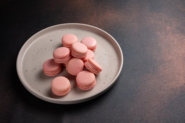 Amaretti rosa su un piatto su un tavolo scuro