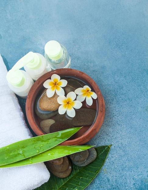 Ambiente spa o benessere con fiori tropicali ciotola di asciugamano per l'acqua e tubo crema Vista dall'alto