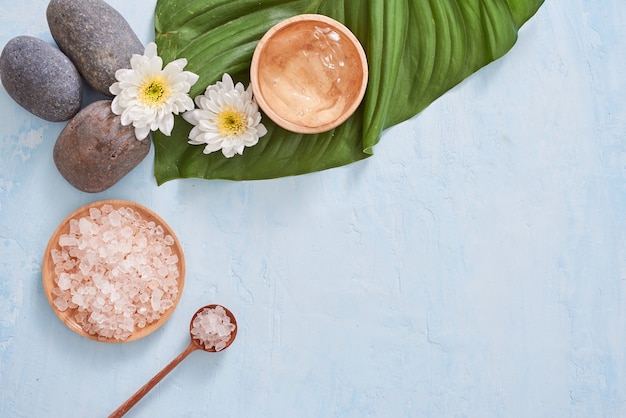 Ambiente termale con crema cosmetica, gel, sale da bagno e foglie di felce su sfondo blu