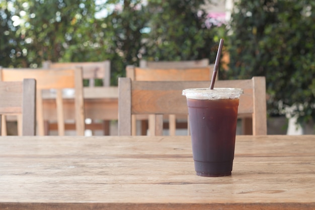 Americano ha ghiacciato il caffè in tazza di plastica asportabile sullo scrittorio di legno nel negozio del caffè