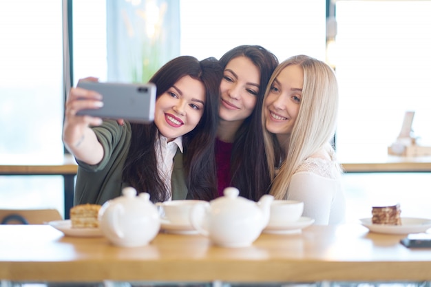 Amiche che fanno selfie in caffè