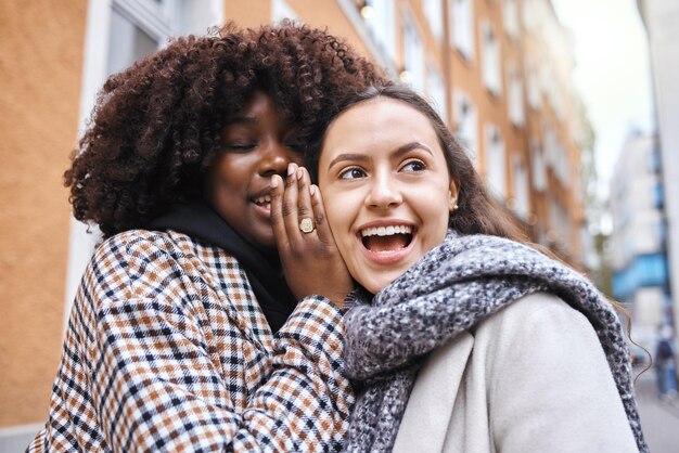 Amiche e pettegolezzi in città che sussurrano nelle orecchie per conversazioni o discussioni segrete Donne felici scioccate o sorprese in annunci di comunicazioni private o segreti per strada