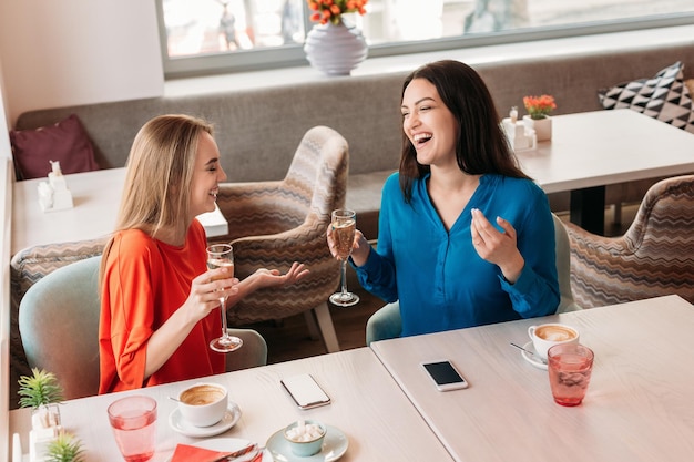 Amiche felici che chiacchierano e bevono champagne al bar