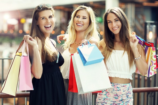 amiche felici che fanno shopping nel centro commerciale?