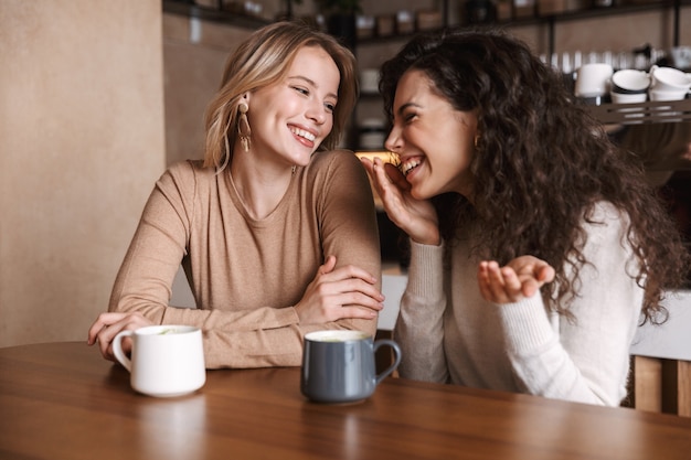 amiche felici sedute al bar che parlano tra loro bevendo tè o caffè