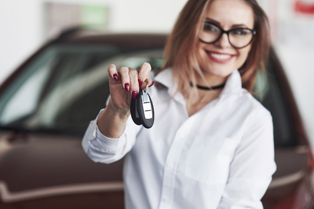 Amichevole manager femminile si leva in piedi contro l'auto rossa nel salone dell'automobile