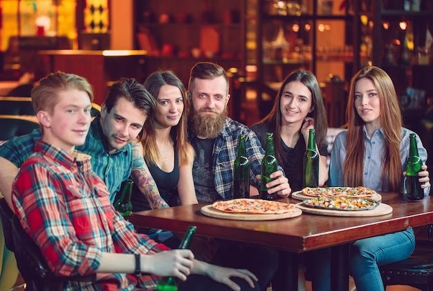 Amici a bere qualcosa e mangiare pizze in un bar