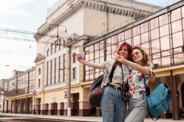 Amici a metà tiro che prendono selfie alla stazione ferroviaria