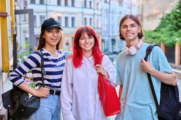 Amici adolescenti sorridenti felici che guardano la macchina fotografica all'aperto sulla strada della città