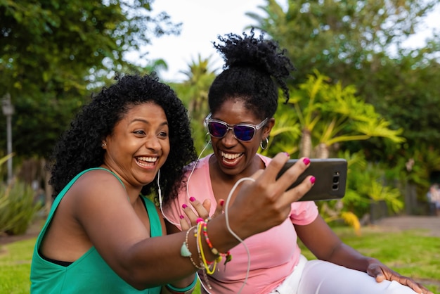 Amici afro che ascoltano musica con cuffie e cellulare