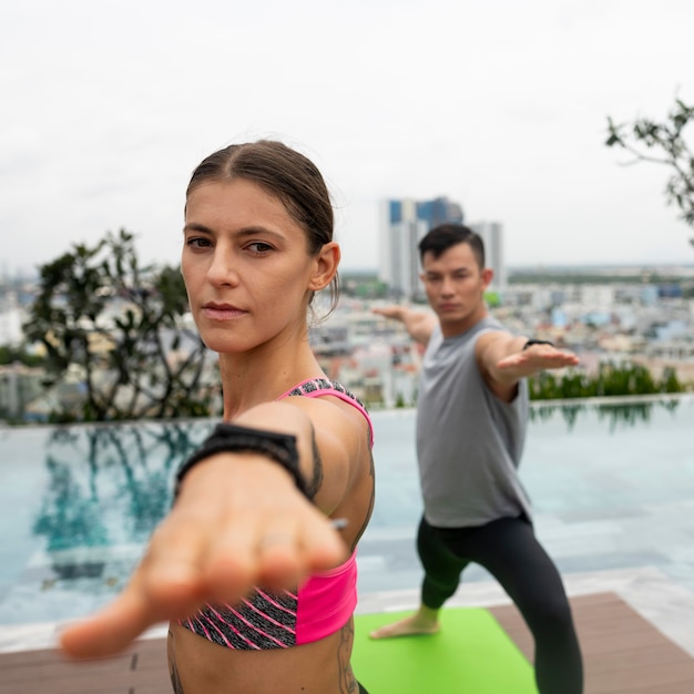 Amici all'aperto che praticano posizioni yoga in piscina