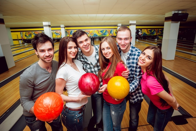 Amici allegri alla pista da bowling con le palle.