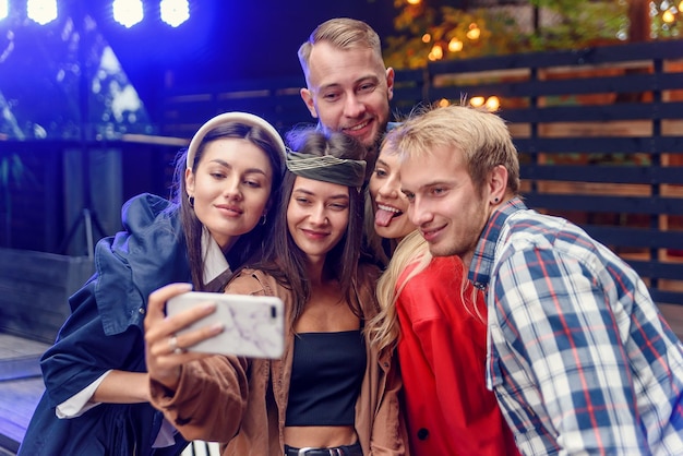 Amici allegri e alla moda che si fanno un selfie insieme alla festa tutti sorridono e si divertono