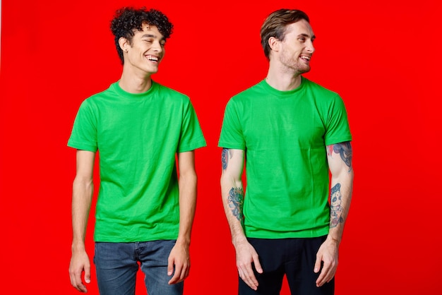 Amici allegri in magliette verdi sono in piedi accanto a uno sfondo rosso