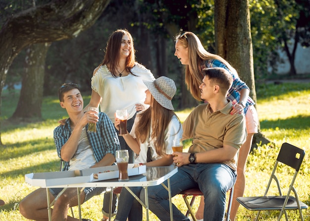 Amici allegri sul picnic nel parco. Mangiare la pizza