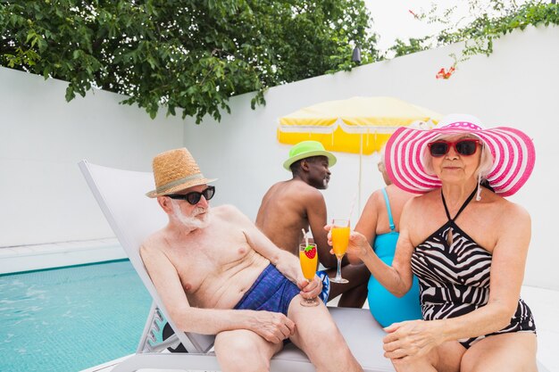 Amici anziani alla festa in piscina durante l'estate