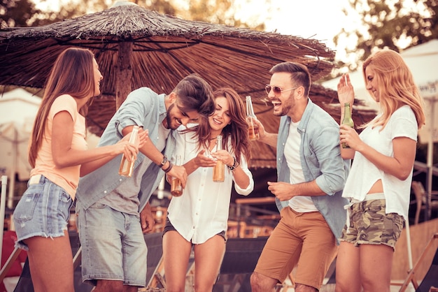 Amici che ballano in spiaggia in una giornata di sole