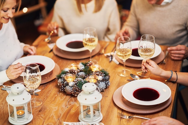 Amici che celebrano la festa di Natale tenendo il vino. Foto di alta qualità