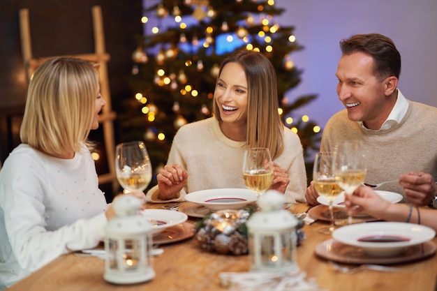 Amici che celebrano la festa di Natale tenendo il vino. Foto di alta qualità