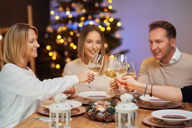 Amici che celebrano la festa di Natale tenendo il vino. Foto di alta qualità