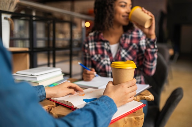 Amici che fanno i compiti insieme mentre prendono il caffè