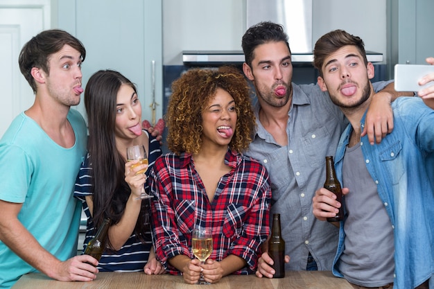 Amici che fanno i fronti mentre prendono selfie in cucina