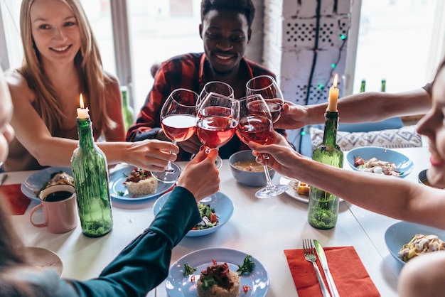 Amici che fanno il brindisi intorno al tavolo a cena.