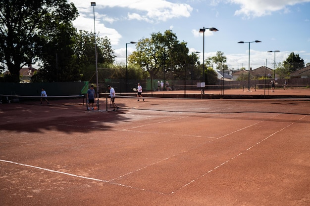 amici che giocano a tennis su un campo di argilla che innaffiano e insaccano un campo d'argilla che fanno la manutenzione del campo di tennis