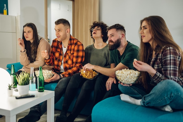 Amici che guardano film a casa e mangiano spuntini