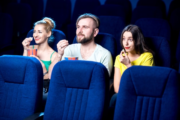 Amici che guardano film seduti insieme a popcorn al cinema