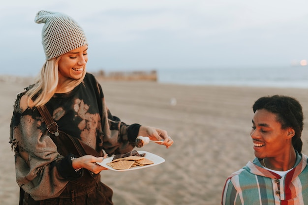 Amici che hanno s&#39;mores in spiaggia