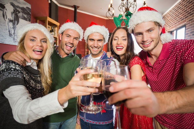 Amici che indossano cappelli di Natale che tostano