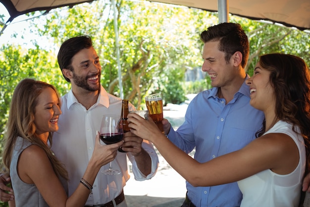 Amici che interagiscono mentre tostano vetro e bottiglia di alcol al bancone