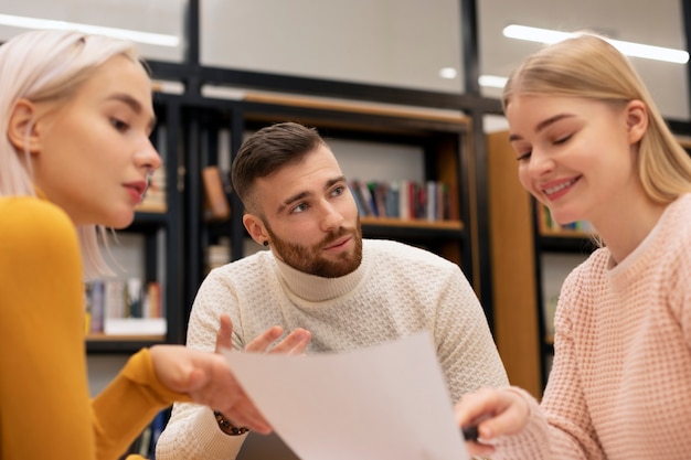 Amici che leggono documenti in una biblioteca durante la sessione di studio